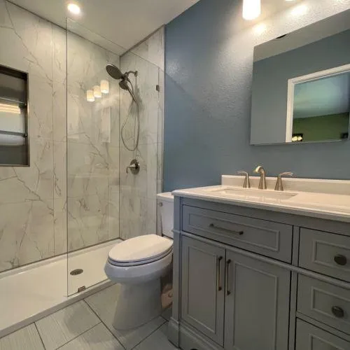 Bathroom renovation featuring marble walls, a spacious walk-in shower, and a modern double vanity.
