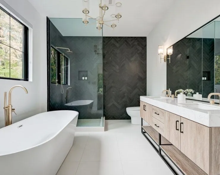 A modern bathroom featuring black tile walls, marble countertops, and a stylish wooden vanity.