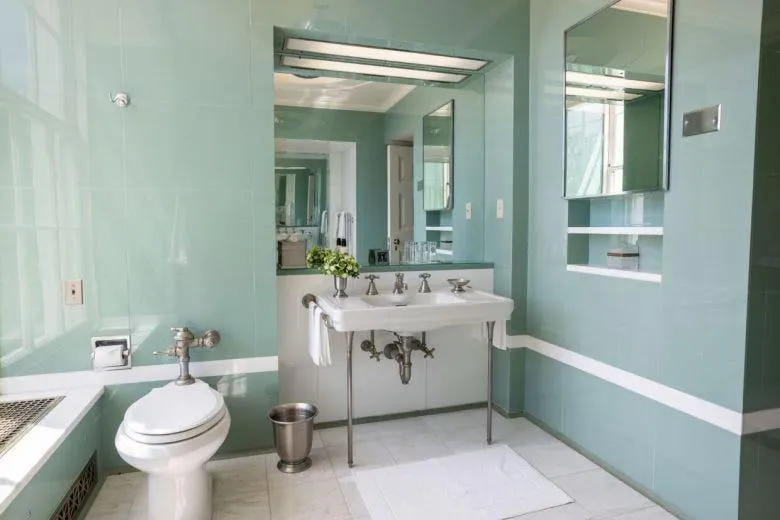 Bathroom renovation with contemporary finishes, including a white toilet, double sinks, and a tiled floor.