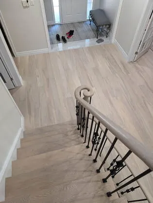 Staircase with hardwood steps and a black railing.