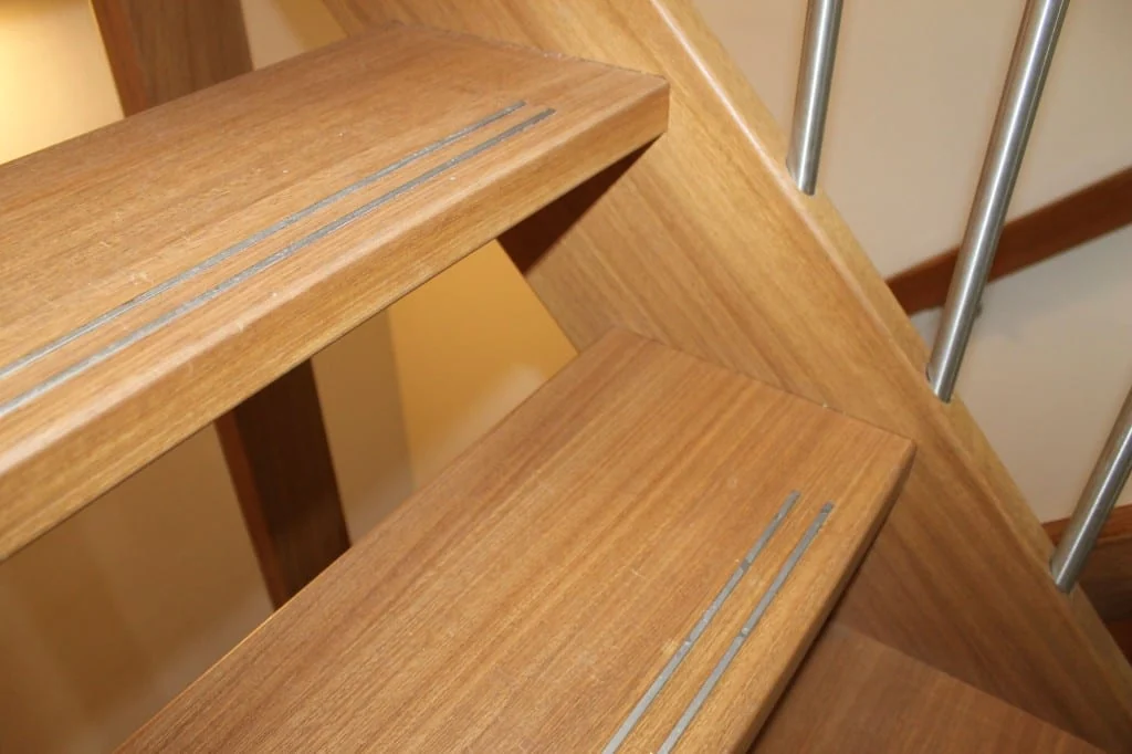 Close-up of finished wood stair treads with two parallel silver metal strips in each tread